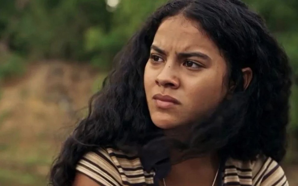 A atriz Bella Campos com expressão séria, olhando para a esquerda, em cena externa de Pantanal