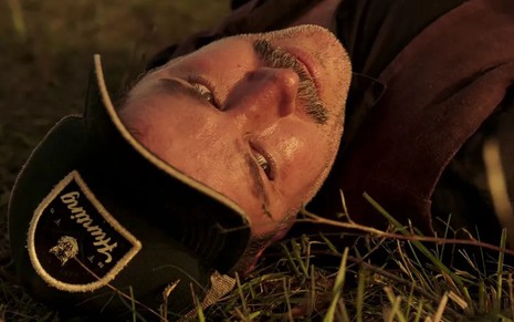 O ator Murilo Benício como Tenório em Pantanal; ele está deitado na grama após ser atacado, olhando para cima com cara de dor