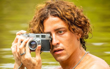 Jove (Jesuíta Barbosa) usa câmera fotográfica enquanto toma banho de rio no Pantanal
