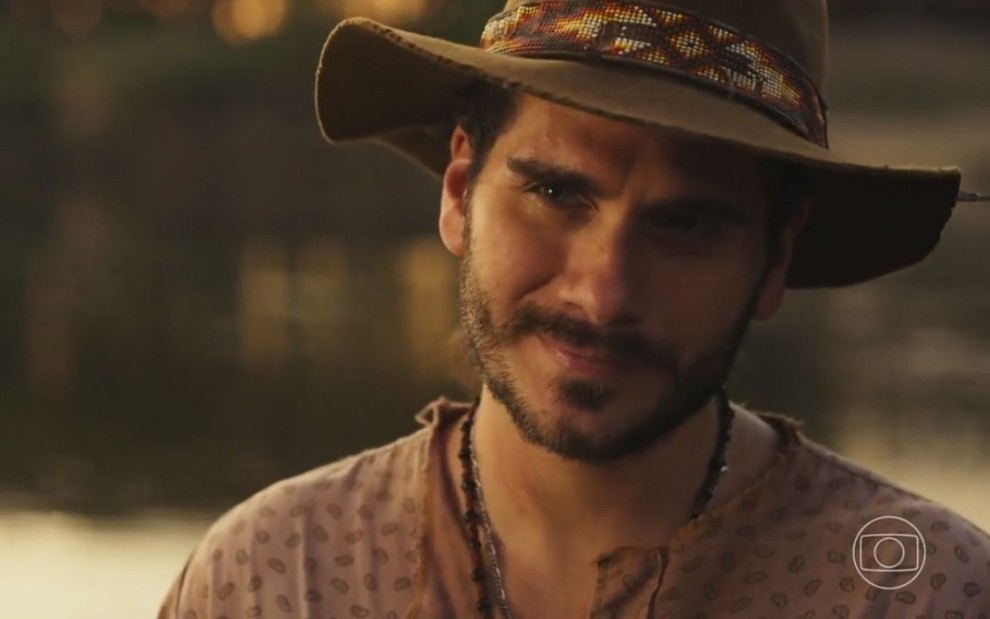 O ator Gabriel Sater como Trindade em Pantanal; ele está de chapéu, olhando para frente e sorrindo