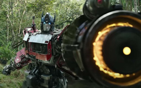 Optimus Prime ergue o braço esquerdo, transformado em um disparador de lasers, em cena de Transformers: O Despertar das Feras