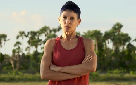 Shirley Miranda, participante de No Limite 2022, está de braços cruzados com a paisagem de uma praia ao fundo