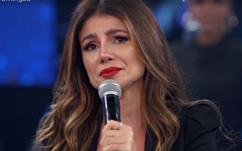 A cantora Paula Fernandes com expressão de choro e microfone na mão durante participação no Domingão com Huck