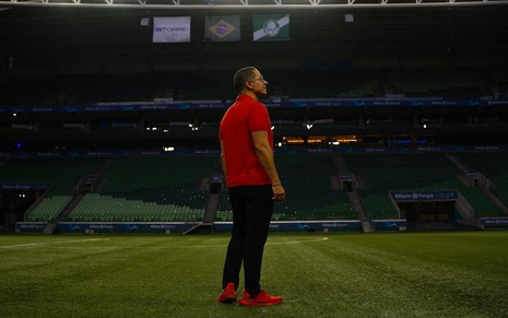 O coach Paulo Vieira no gramado do Allianz Parque, estádio do Palmeiras, que está vazio; ele veste camisa polo e tênis vermelhos