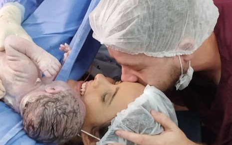 Fernanda Malta segura um recém-nascido no colo ao lado de Pedro Malta