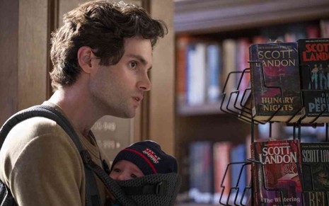 Penn Badgley carregando um bebê em cena de You