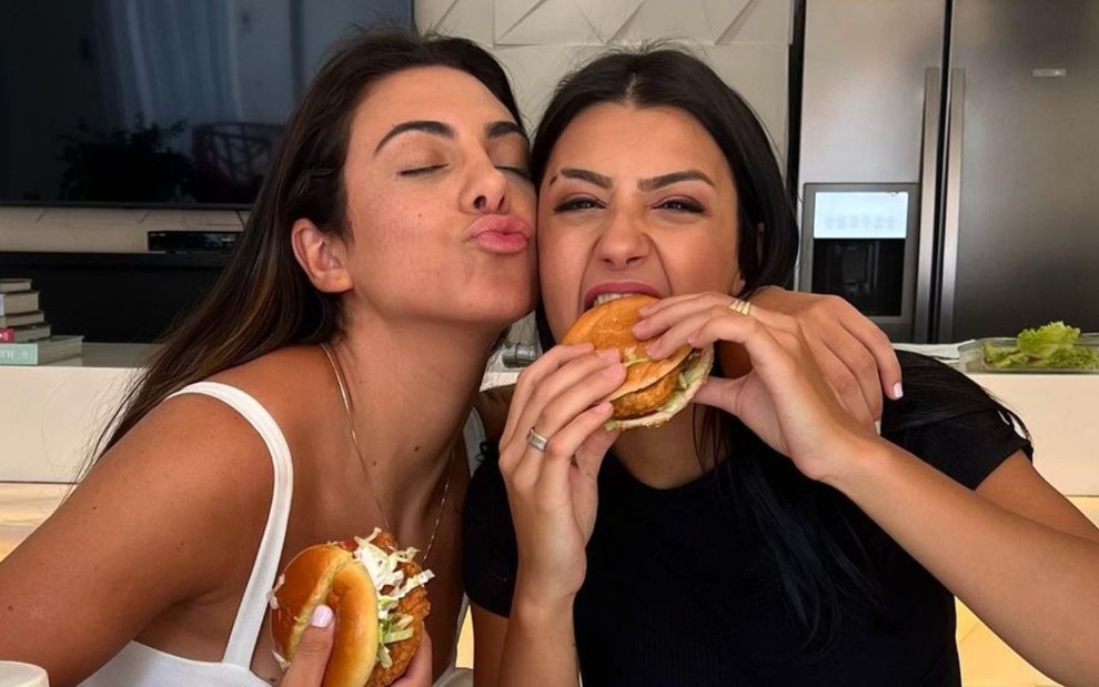 Imagem de Pétala Barreiros (à esq.) e Bia Miranda comendo hamburguer