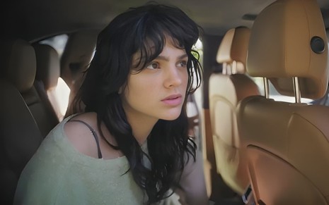 A atriz Debora Ozório em cena de Terra e Paixão, com expressão de tensão, dentro de carro