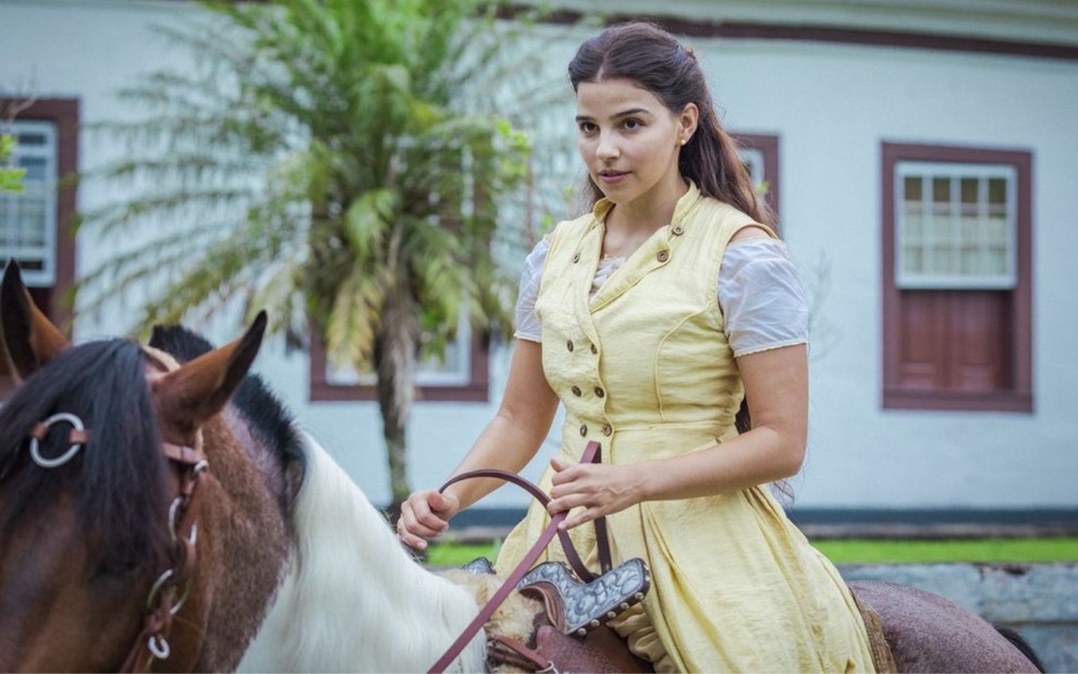 Pilar (Gabriela Medvedovski) está em cima de um cavalo em cena de Nos Tempos do Imperador