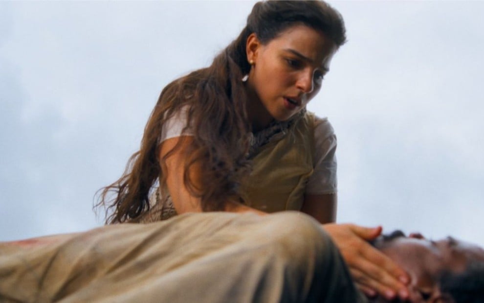 Pilar (Gabriela Medvedovski) socorre Jorge/Samuel (Michel Gomes), que está caído no chão em cena de Nos Tempos do Imperador