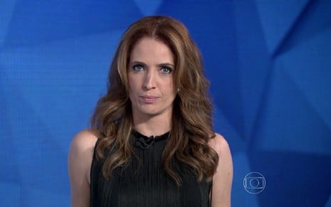Poliana Abritta com um vestido preto no cenário azul do Fantástico, da Globo
