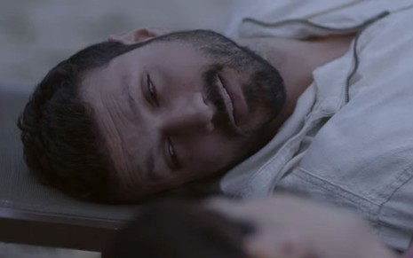 O ator Murilo Cezar como Marcelo em Poliana Moça; ele está deitado de lado, olhando para frente com cara de cansado