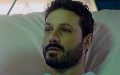 O ator Murilo Cezar como Marcelo em Poliana Moça; ele está deitado na cama olhando para frente com cara de frágil