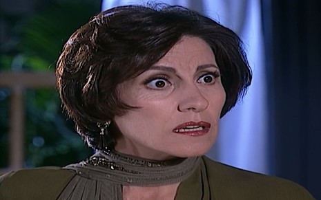 A atriz Cassia Kis como Adma em Porto dos Milagres; ela está olhando para o lado com cara de assustada