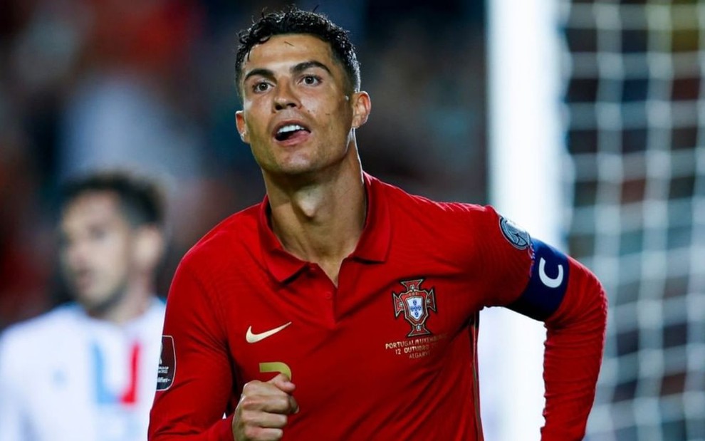 Cristiano Ronaldo, veste uniforme vermelho com dourado e corre em campo pela seleção portuguesa