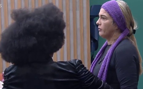 Michele veste jaqueta preta; Andreia usa lenço na cabeça e veste blusa azul