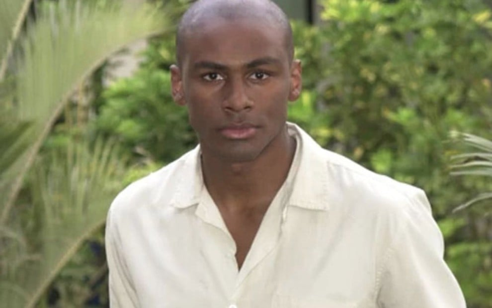 O ator Taiguara Nazareth de camisa branca e expressão séria, posa para foto em área externa