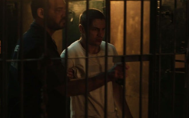 Gabriel Leone, com a cabeça raspada, é segurado por homem vestido como policial em cena de Dom
