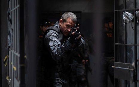 Malvino Salvador empunha uma arma em cena da série Negociador, do Prime Video
