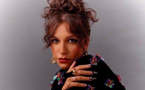 Priscilla Alcantara em foto publicada no Instagram: cantora está com jaqueta preta com detalhes coloridos, e olha para a câmera com a cabeça em cima do ombro