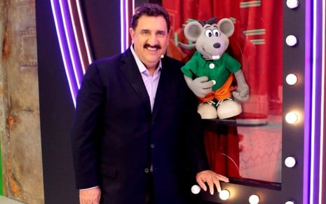 O apresentador Ratinho sorri ao lado de seu mascote, Xaropinho, no estúdio do Programa do ratinho no SBT
