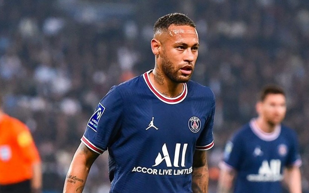 Neymar com uma camisa azul do PSG, em campo, marcando a bola durante um jogo do Campeonato Francês