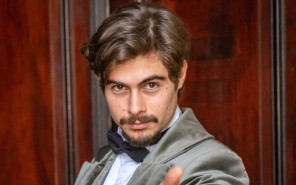 Rafael Vitti usa terno e está caracterizado como Davi, protagonista da novela Além da Ilusão