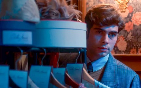 O ator Rafael Vitti como Davi em Além da Ilusão; ele está atrás de uma estante, olhando atento para o lado