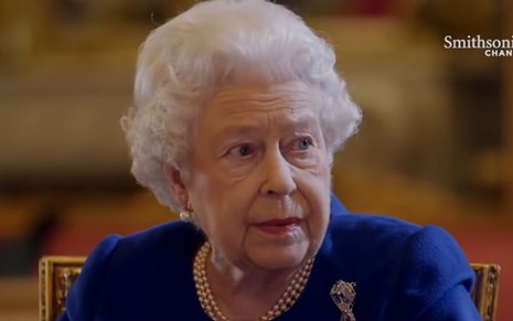 Rainha Elizabeth 2ª de terno azul, colar de pérolas e expressão séria