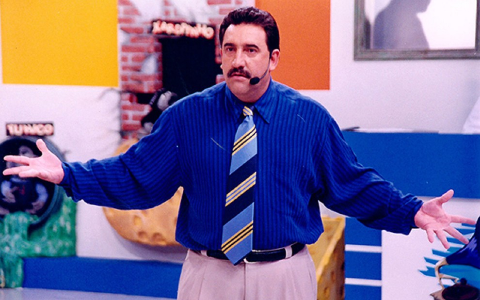 Ratinho com camisa azul e gravata chamativa em seu programa no SBT em 1998