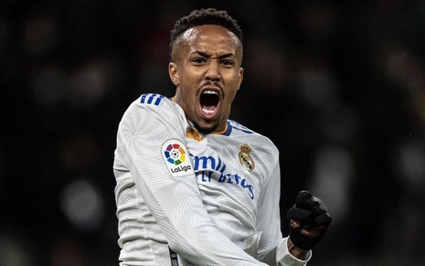 Éder Militão, do Real Madrid, grita ao comemorar gol e veste uniforme branco com detalhes azuis