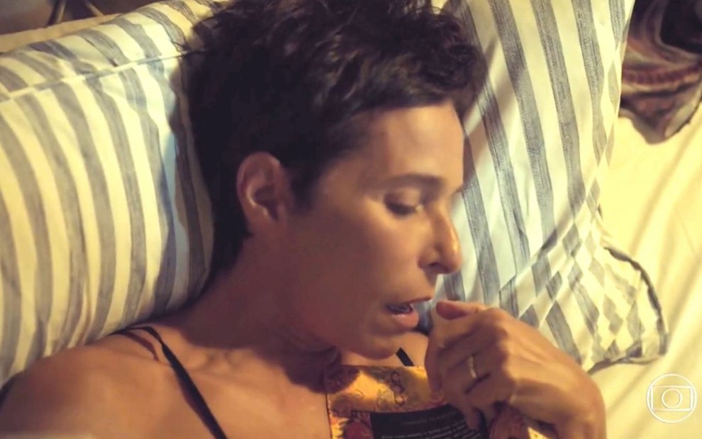 A atriz Andrea Beltrão de olhos fechados numa cama, em cena em que sua personagem Rebeca, de Um Lugar ao Sol, se masturba