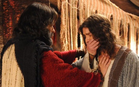 Guilherme Winter grava cena com a mão no peito de Petrônio Gontijo, que está com a mão no rosto, como Moisés e Arão