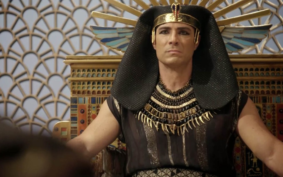 O ator Fernando Pavão como Sheshi com uma expressão de desconforto sentado no trono do Egito em cena de Gênesis