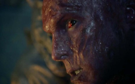 O ator Igor Rickli em um close no seu rosto, ele está completamente queimado, com feriadas de 3º grau, com os olhos bastante vermelhos, como Lúcifer em cena de Gênesis