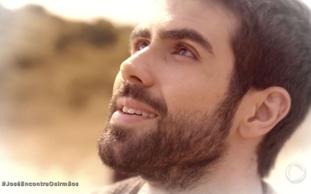 O ator Juliano Laham caracterizado como o personagem José sorri enquanto olha para cima em cena de Gênesis, novela bíblica da Record
