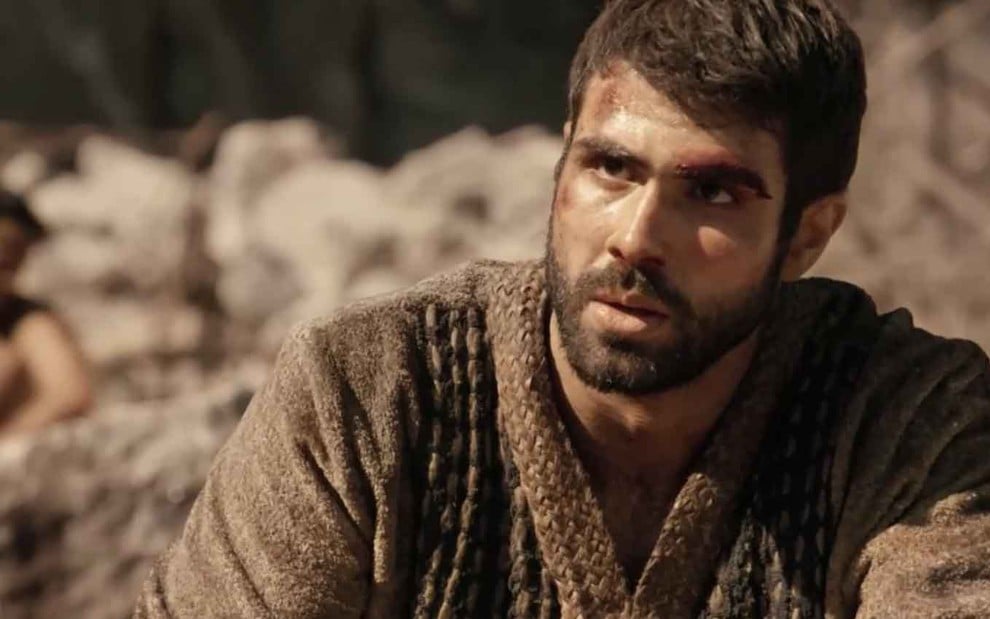 O ator Juliano Laham caracterizado como José com um machucado na testa, que sangra, e cara de espanto em cena de Gênesis
