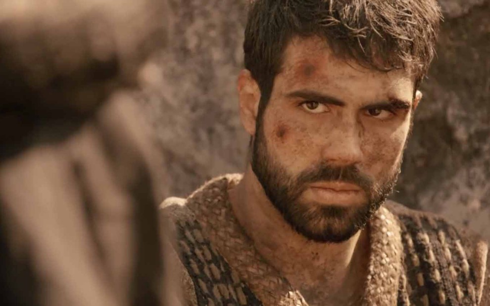 O ator Juliano Laham com feriadas no rosto e expressão de medo como José em cena de Gênesis