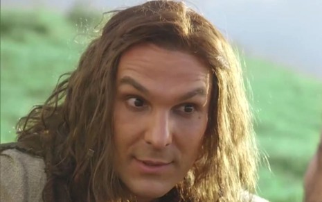 Igor Rickli em cena de Gênesis: caracterizado como Lúcifer, personagem está com cabelos longos e olha com interesse para alguém fora do quadro