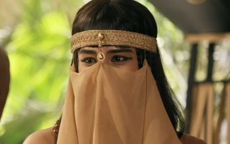 Meritre (Marcelle Bessa) está com peruca preta lisa, usa véu que cobre sua boca e usa maquiagem no olho em cena de Gênesis