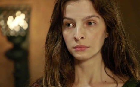 A atriz Michelle Batista, com cara fechada, caracterizada como Lia em cena de Gênesis