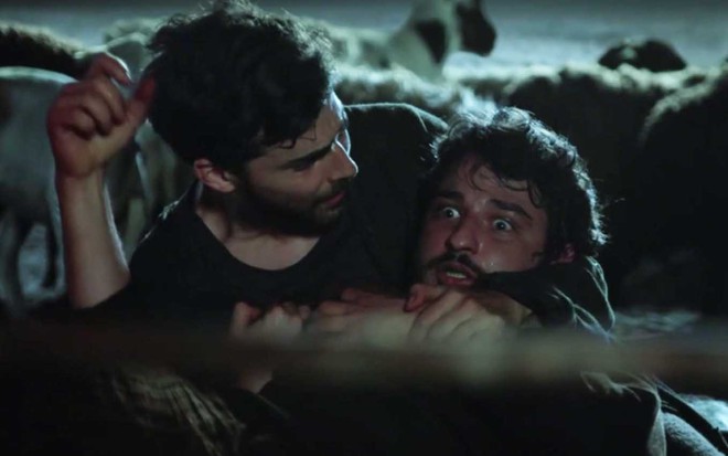 O ator Miguel Coelho como Jacó acode o ator César Cardadeiro, com olhos arregalados como se não conseguisse respirar, como Éder em cena noturna de Gênesis