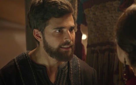 O ator Miguel Coelho caracterizado como Jacó e com expressão de raiva, com os olhos arregalados, em cena noturna de Gênesis
