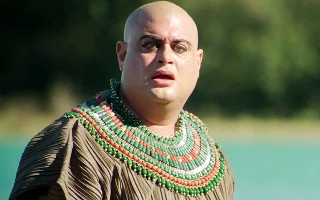 O ator Ricardo Lyra com expressão de surpresa diante de um rio como o Adurrá em cena de Gênesis
