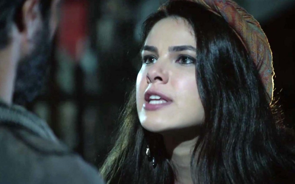 A atriz Thaís Melchior com expressão de raiva como Raquel em uma cena noturna de Gênesis
