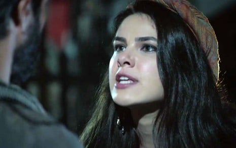 A atriz Thaís Melchior com expressão de raiva como Raquel em uma cena noturna de Gênesis