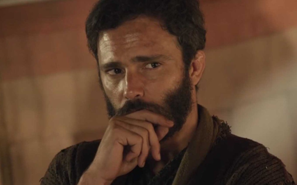 O ator Thiago Rodrigues leva a mão direita a boca, em sinal de sofrimento e inquietação, como o Judá em cena de Gênesis