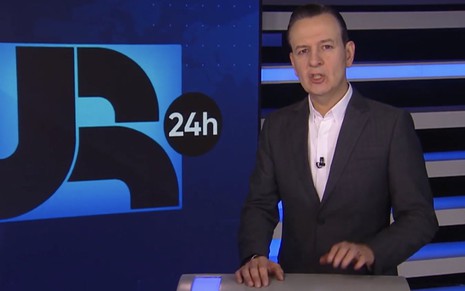 O jornalista Celso Zucatelli usa terno escuro e camisa branca no cenário do JR 24 Horas, da Record
