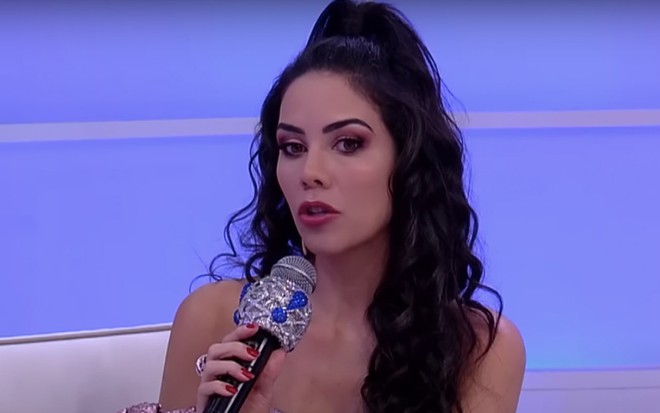 A apresentadora Daniela Albuquerque segura um microfone no sofá do Sensacional, na RedeTV!