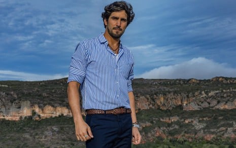 Renato Góes caracterizado como seu personagem em Mar do Sertão: ele está de blusa de botão e calça comprida